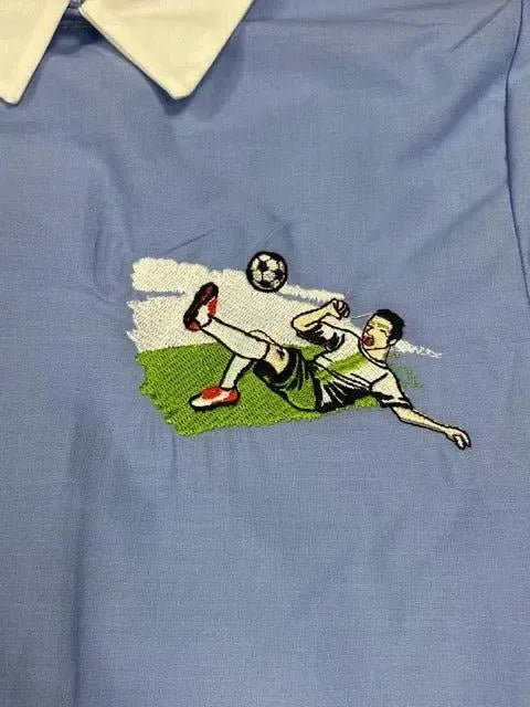 Grembiule scuola elementare bambino celeste con abbottonatura laterale ricamo Calcio MN904